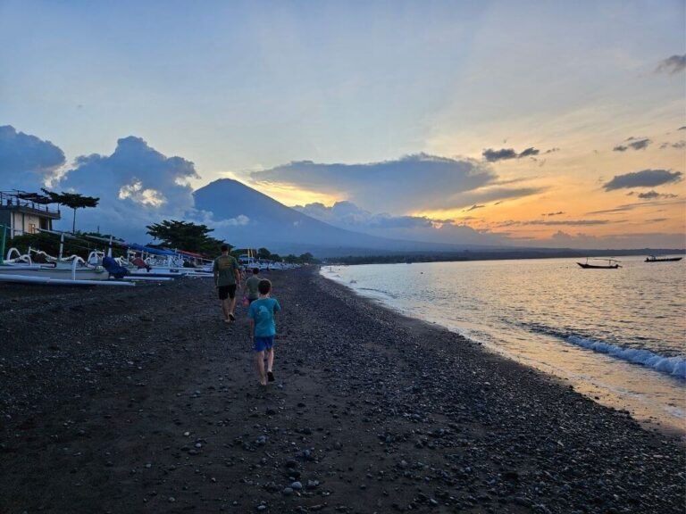 Kinderen wandelen bij zonsondergang op het strand van Amed Bali met Mount Agung op de achtergrond tijdens een half jaar reizen met kinderen