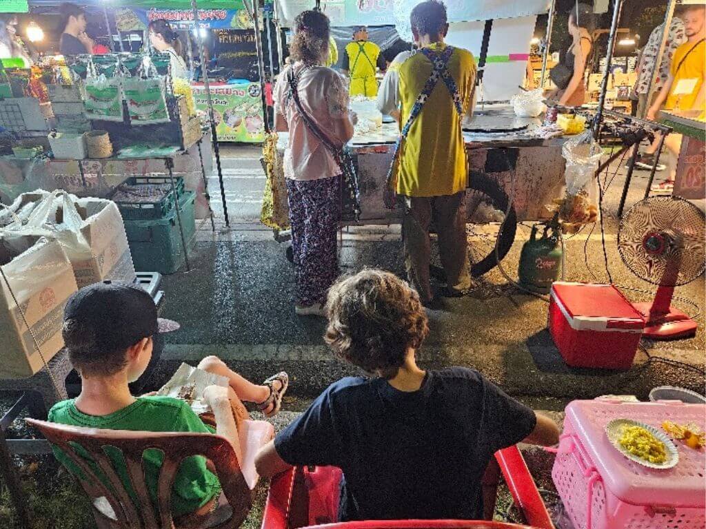 Kinderen proeven streetfood op de Ong Gaan Tolasap night market in Ayutthaya tijdens een vakantie in Thailand met kinderen