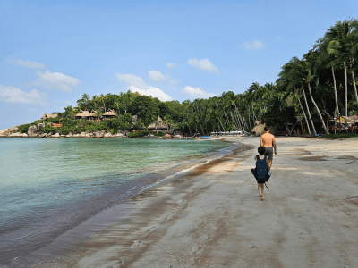 Kinderen lopen op een wit zandstrand tussen de palmbomen op Koh Tao
