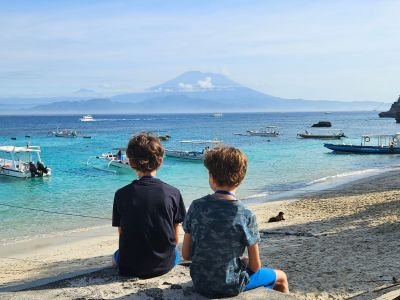 Kinderen op het strand van Nusa Lembongan met uitzicht op de vulkaan op Bali tijdens een vakantie met kinderen