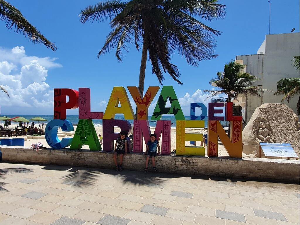 Kinderen poseren bij de kleurrijke Letras Turísticas in Playa del Carmen tijdens een vakantie in Mexico met kinderen