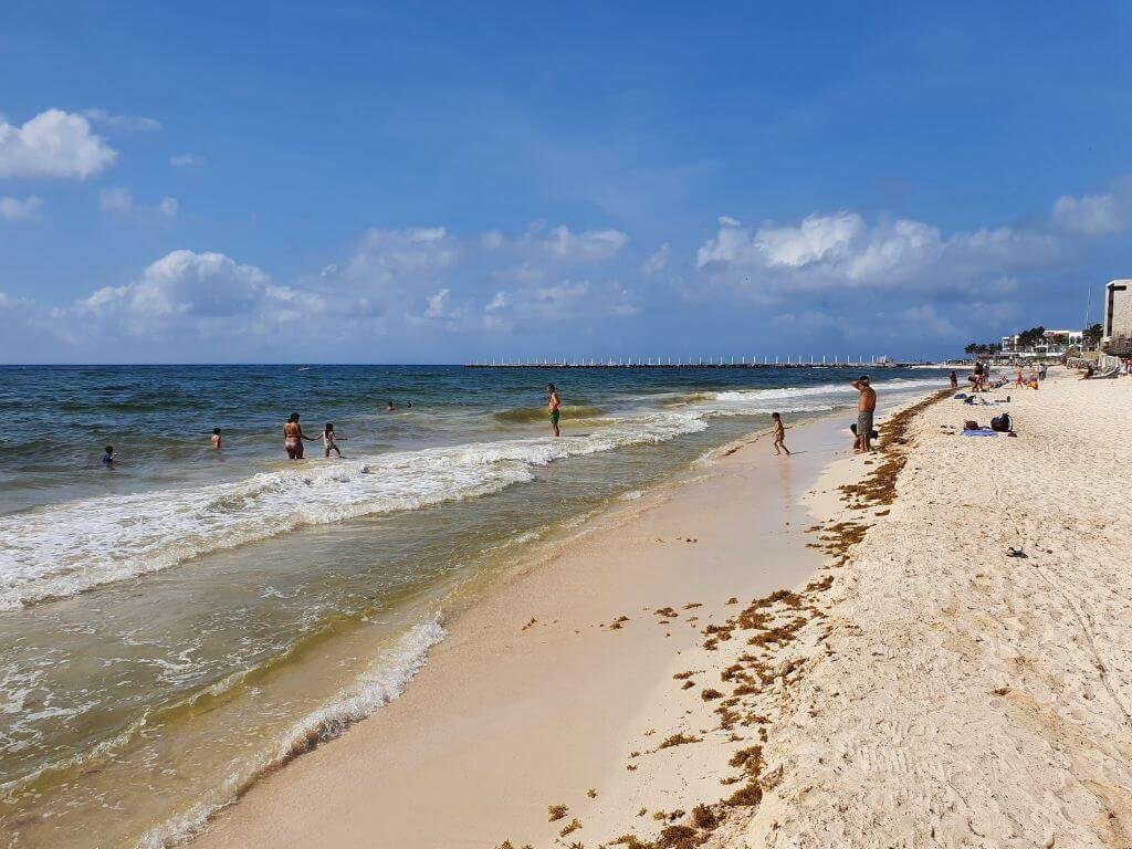 Kinderen spelen in het zand op het brede strand van Playa del Carmen tijdens een gezinsvakantie in Mexico met kinderen